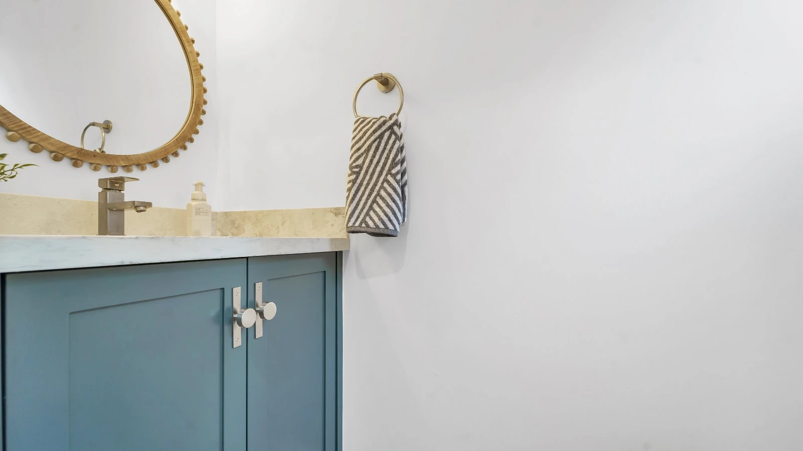 Blue bathroom vanity with gold mirror and towel ring in Oakville
