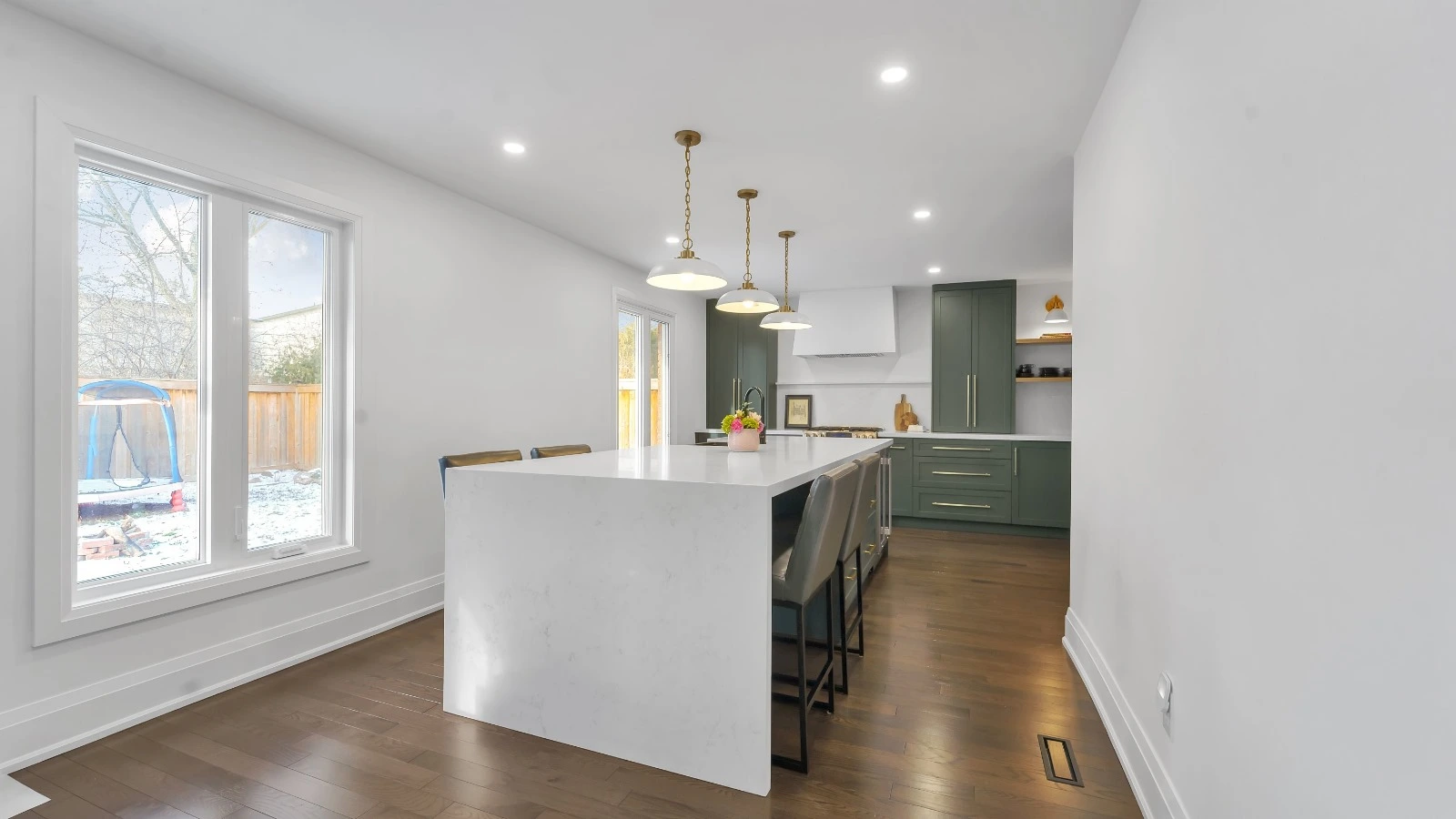 Bright kitchen renovation with a white island and green cabinetry