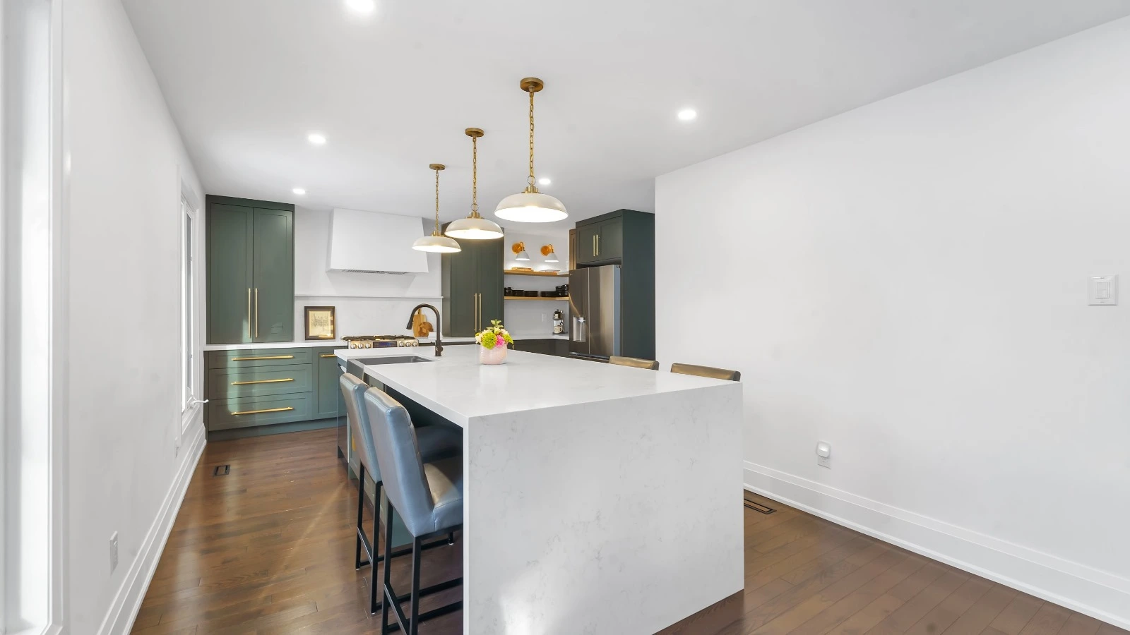Modern open-concept kitchen with green cabinets and a white island in Oakville